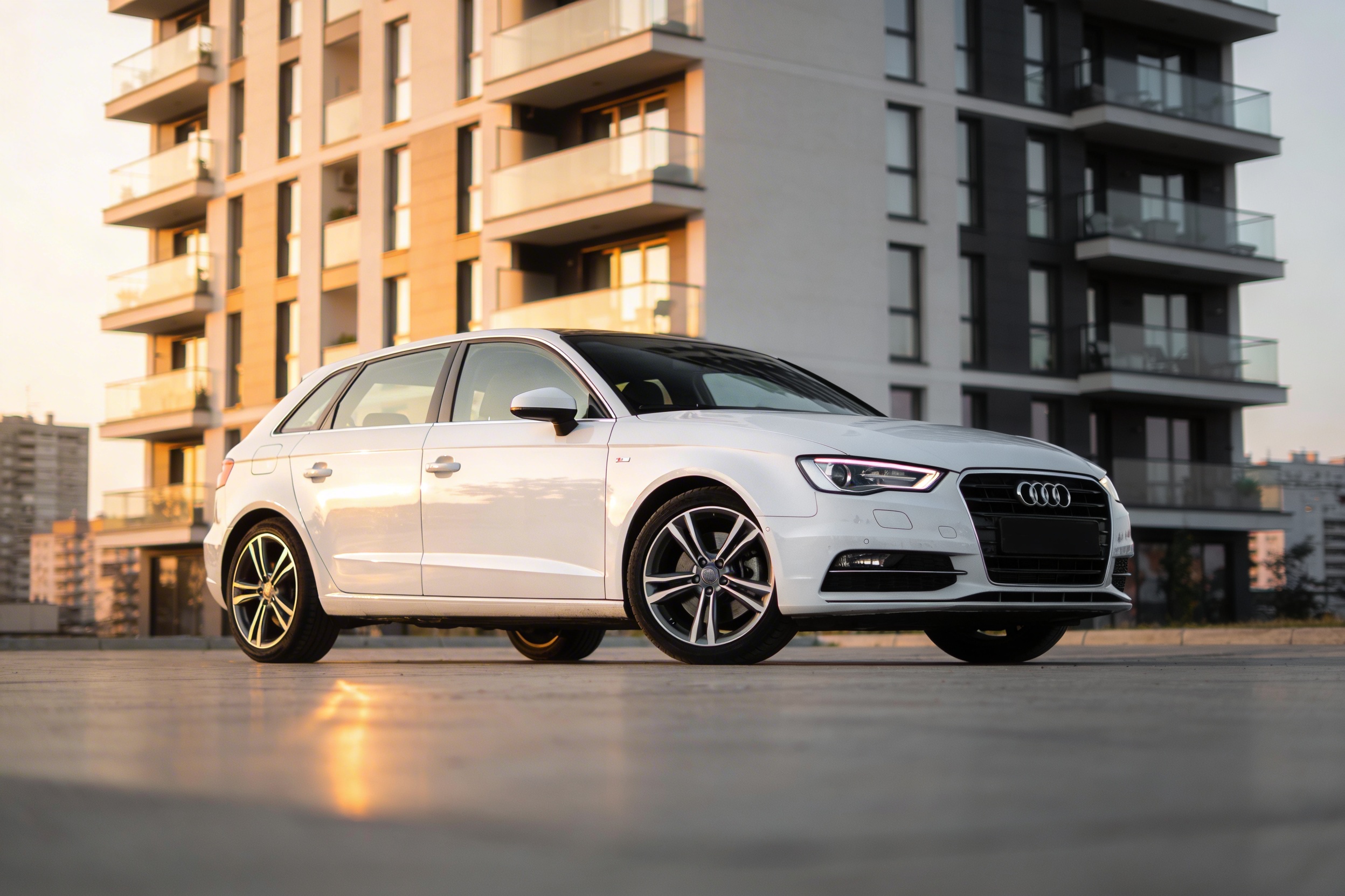 Beli Audi A3 hatchback parkiran ispred moderne zgrade u Beogradu
