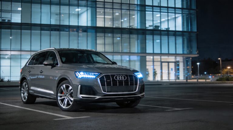 Luksuzni sivi Audi Q7 parkiran ispred poslovnog centra u suton
