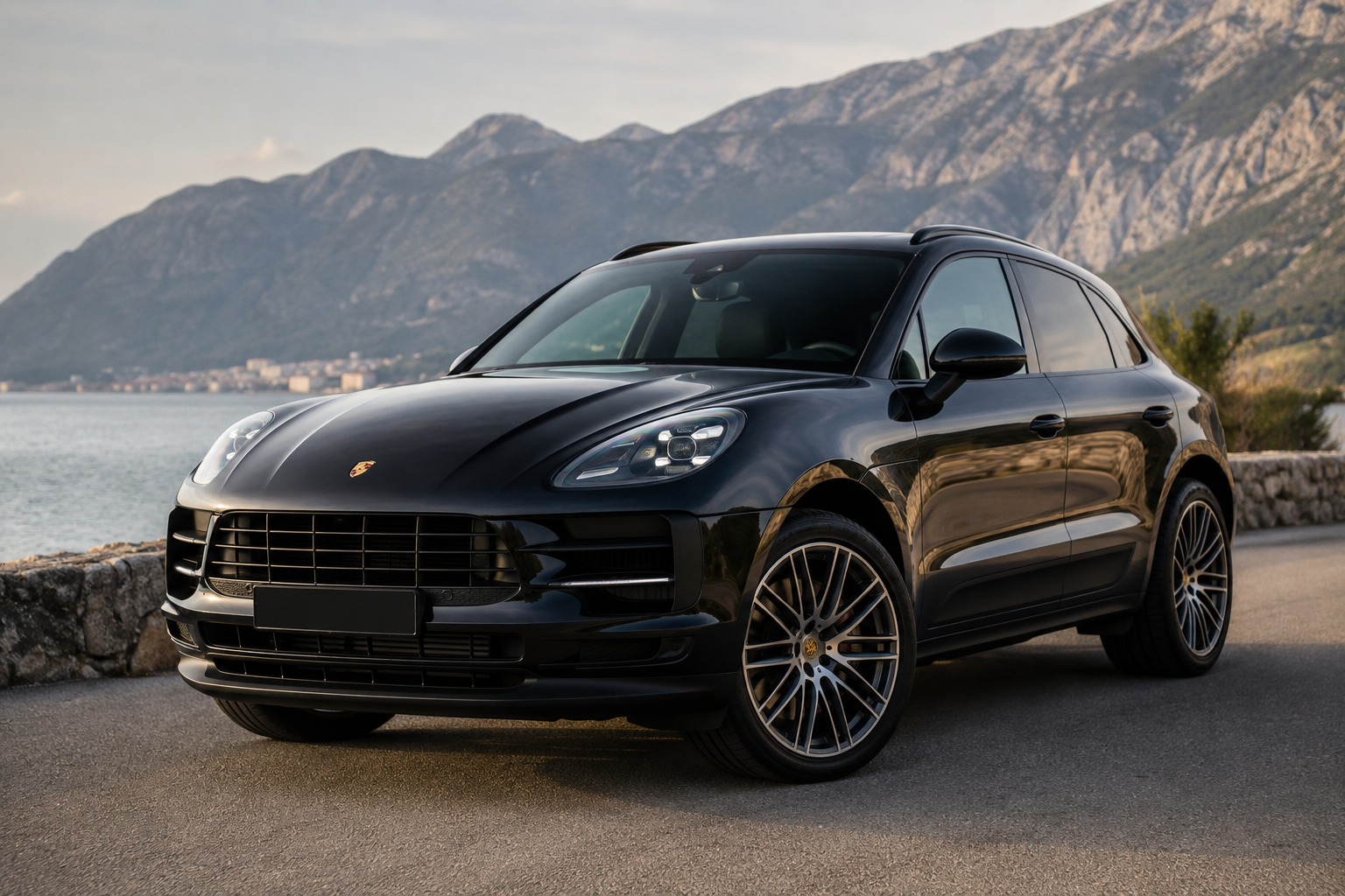 Crni Porsche Macan parkiran pored obale, ilustracija za članak o iskustvima, kvarovima, potrošnji i održavanju modela Porsche Macan.